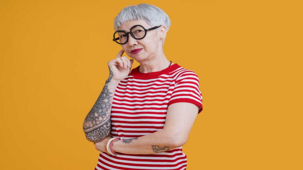 senior asian female grey hair fashioned cloth with tattoo arm standing hand gesture with positive confident expressionold asia woman wear red tshirt carefree lifestyle happiness pension age